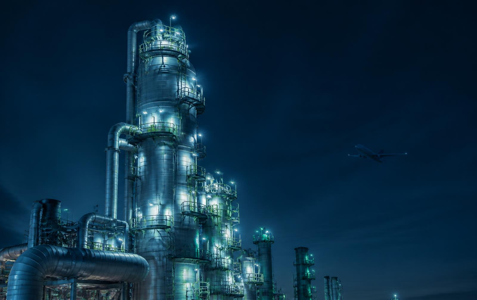 Refinery fractionation columns at dusk with aviation context in the distance